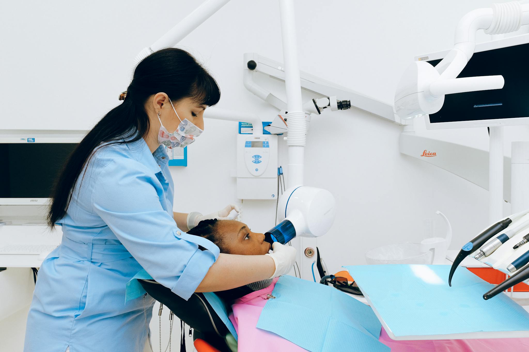 Dentist performs a dental procedure using advanced equipment in a modern clinic setting.